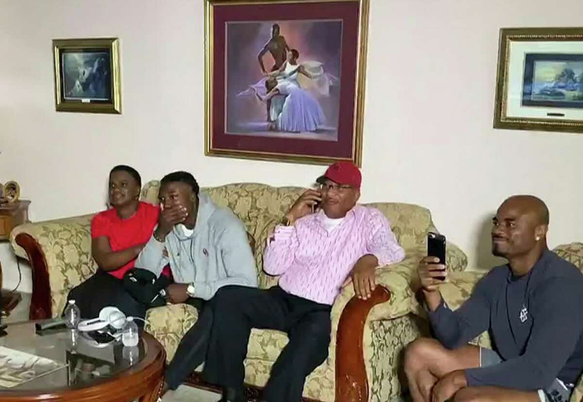 In this still image from video provided by the NFL, Kenneth Murray, second from left, watches the NFL football draft Thursday, April 23, 2020, in Missouri City, Texas. Murray was chosen by the Los Angeles Chargers. (NFL via AP)