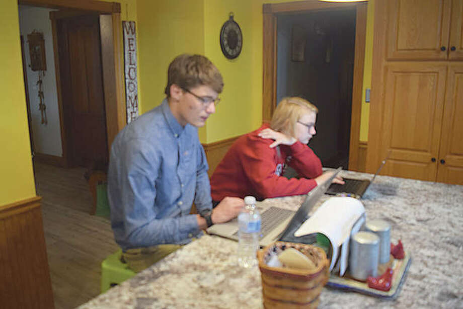 Jacksonville High School senior Xavier Posey works on his laptop next to his sister, Mikaya, a Jacksonville Middle School student. Mikaya said she was inspired to write words of encouragement to seniors like her brother who will not experience a traditional graduation.