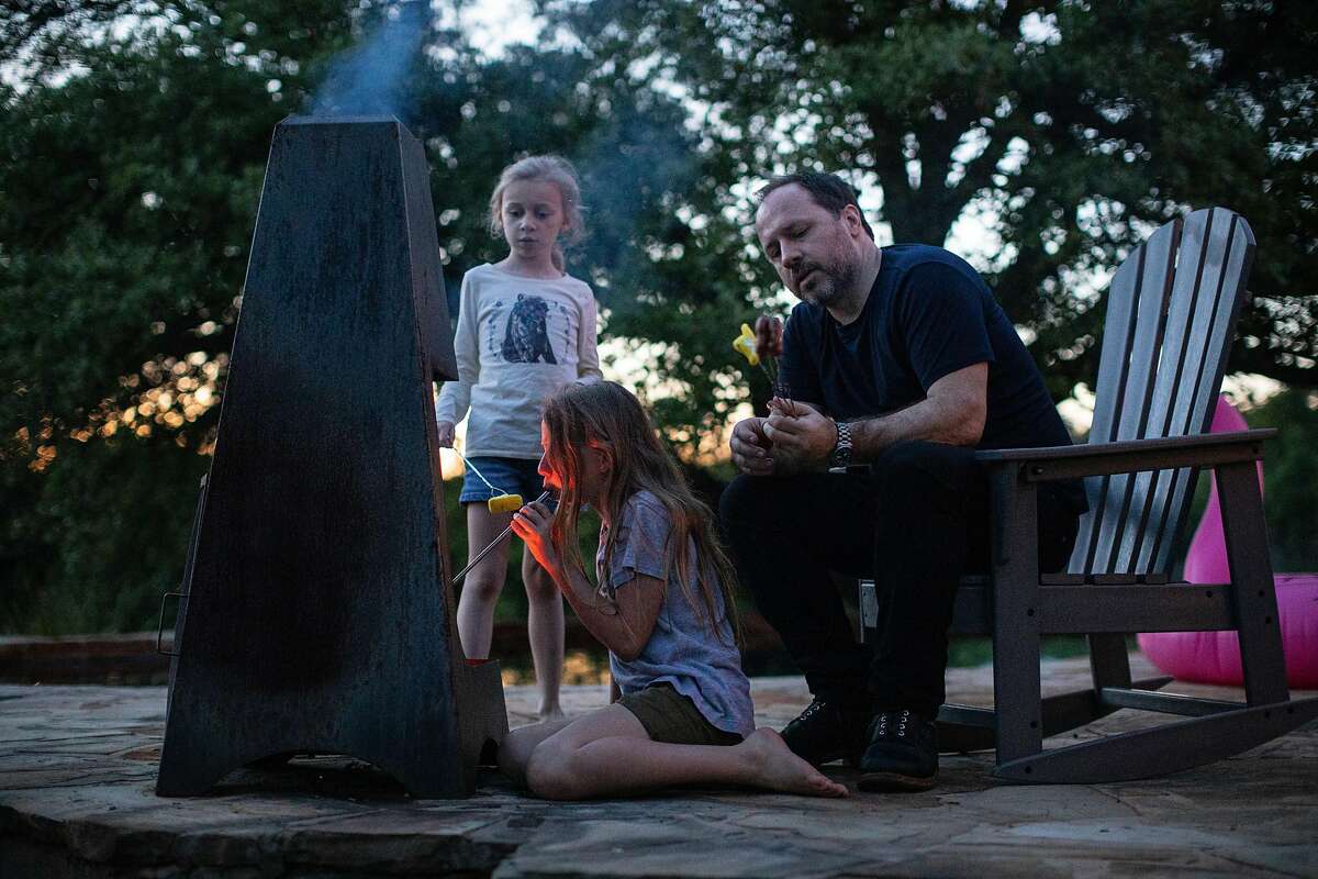 Jon Stokes, deputy editor of an online prepping guide, �The Prepared,� and his daughters maintain a fire with a blowpipe at their home in Georgetown, Texas, April 10, 2020. In tech circles, gearing up for the apocalypse was a clichŽ, but now it�s a credential. (Tamir Kalifa/The New York Times)