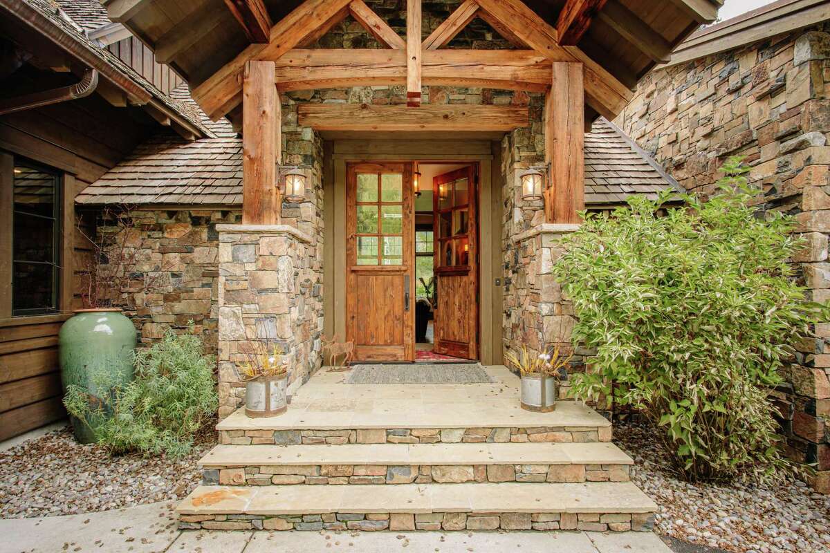 Stacked stone and timber beams fashion the home’s portico.