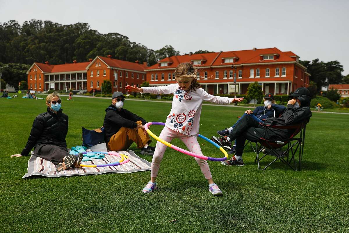 Angie Muscat (center), 6, hula hoops as mom Christina Dam (left), dad Jason Muscat (second from left), grandmother Becky Muscat (second from right) and grandfather Bob Muscat (right) look on at the Main Parade Grounds in the Presidio in San Francisco, California on Sunday, April 26, 2020. Public health officials had feared spring-like weather over the weekend would cause a rush of people to set aside shelter in place mandates and descend upon public parks and beaches, putting themselves at risk to coronavirus exposure.
