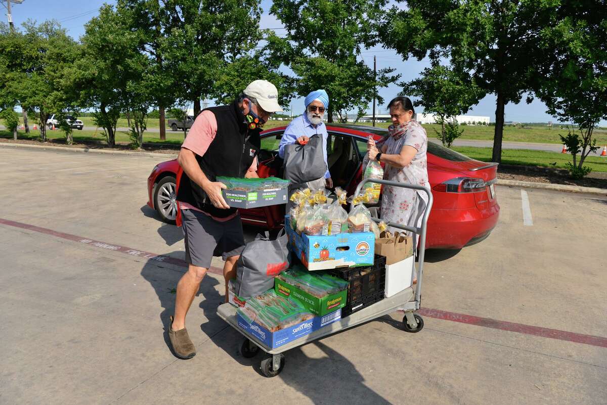 G.P. Singh of the Sikh Dharamsal of San Antonio (center), his wife Winkey (right) and Michael Guerra of the San Antonio Food Bank unload peanut butter and jelly sandwiches that were made by the Sikh Dharamsal for a food distribution at the Food Ban on Saturday.