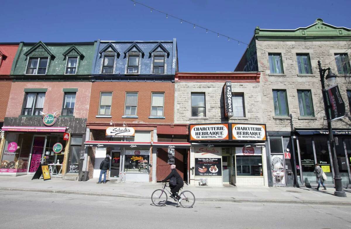 A cyclist rides on St. Laurent Boulevard past Schwartz's deli in Montreal, Quebec, on March 27, 2020.