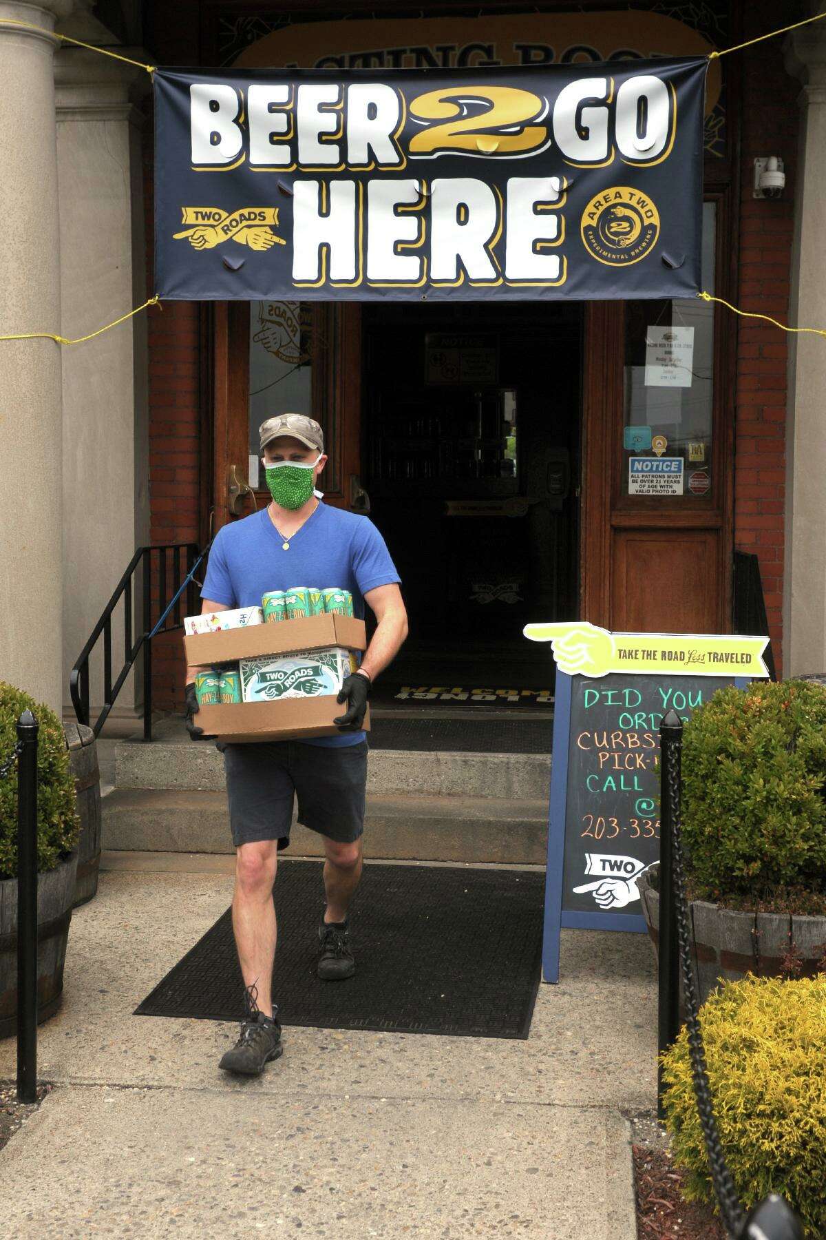 Ted Pert, taproom manager at Two Roads Brewing Company, delivers beer order to a waiting vehicle outside the brewery in Stratford, Conn. April 23, 2020. While Two Road’s taproom remains closed, the brewery is open for online orders and curbside pickup.