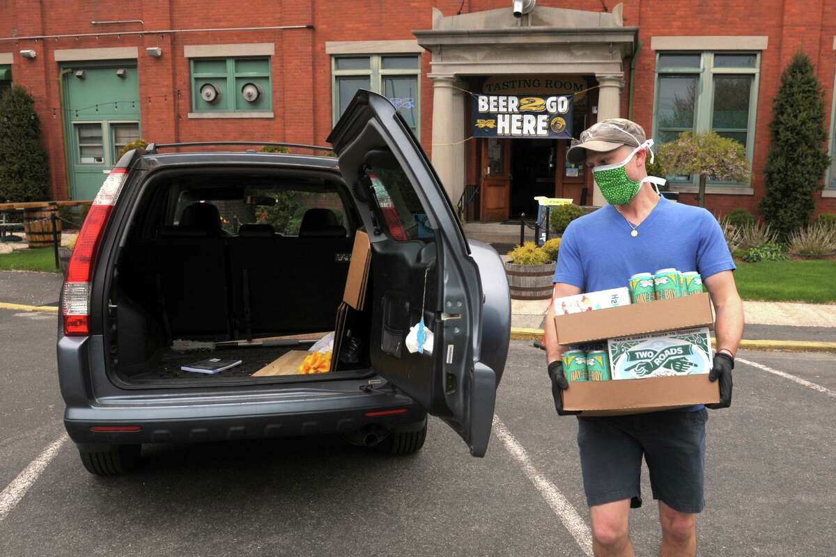 Ted Pert, taproom manager at Two Roads Brewing Company, delivers beer order to a waiting vehicle outside the brewery in Stratford, Conn. April 23, 2020. While Two Road’s taproom remains closed, the brewery is open for online orders and curbside pickup.