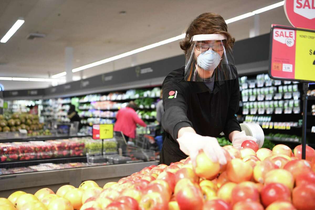 A Stop & Shop employee stocks produce in April 2020 at a store in Simsbury, Conn. Gov. Ned Lamont ordered all business establishments to provide employees masks as of April 20 and until further notice during the 2020 pandemic of the novel coronavirus COVID-19. (Photo courtesy Stop & Shop)