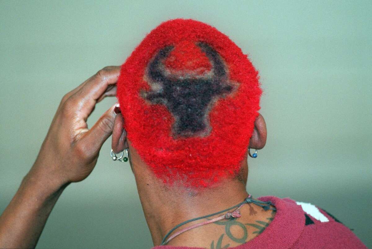 Dennis Rodman, sporting red hair with a Bulls insignia in the back, speaks during a news conference during media day at the Chicago Bulls training center in Deerfield, Ill, Thursday Oct. 5, 1995. Rodman is now a teammate of one-time adversaries Michael Jordan and Scottie Pippen as camp opens Thursday for the team. (AP Photo/Beth A. Keiser)
