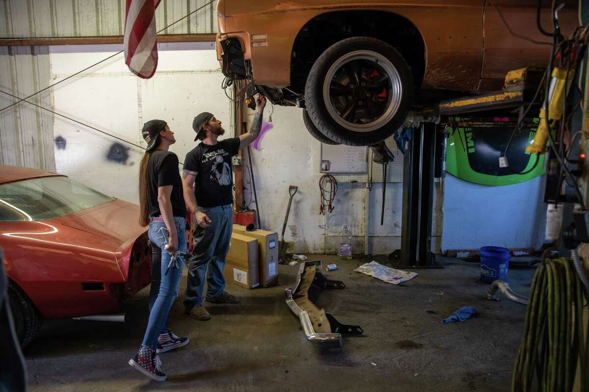 Bud and Amanda Allen check the progress on a client vehicle at their repair shop on Friday, April 24, 2020 in Buda, Texas. The Allens must complete repairs on existing vehicles or ask clients to retrieve incomplete repairs before they move to Tyler.