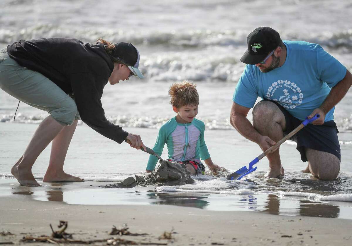 Madison (left) and Jesse Tomaino (right) cover their son's, Miles, 3, legs with sand after the city of Galveston partially reopen public beaches after closing them for nearly a month due to the novel coronavirus outbreak Monday, April 27, 2020, in Galveston. The Tomaino family are from Oregon decided to shelter in place in Galveston instead of driving across the United States to return home.