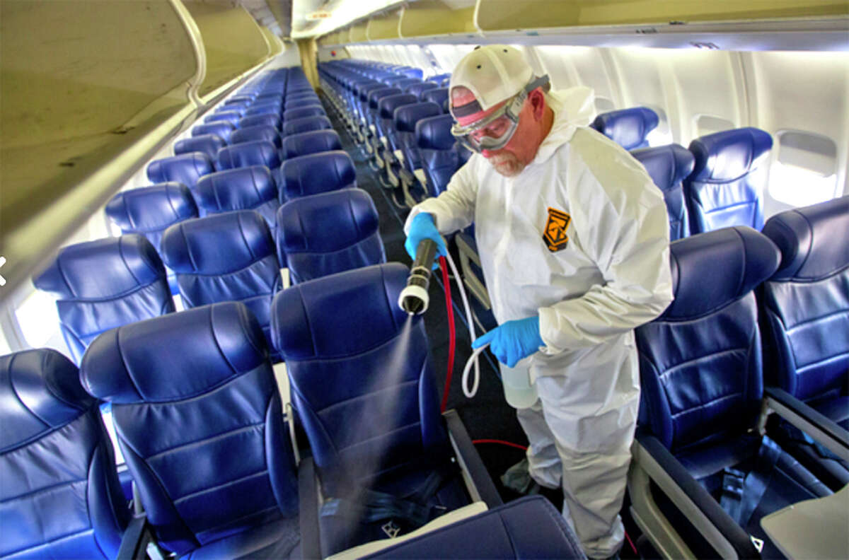 A Southwest employee sprays down passenger seats.