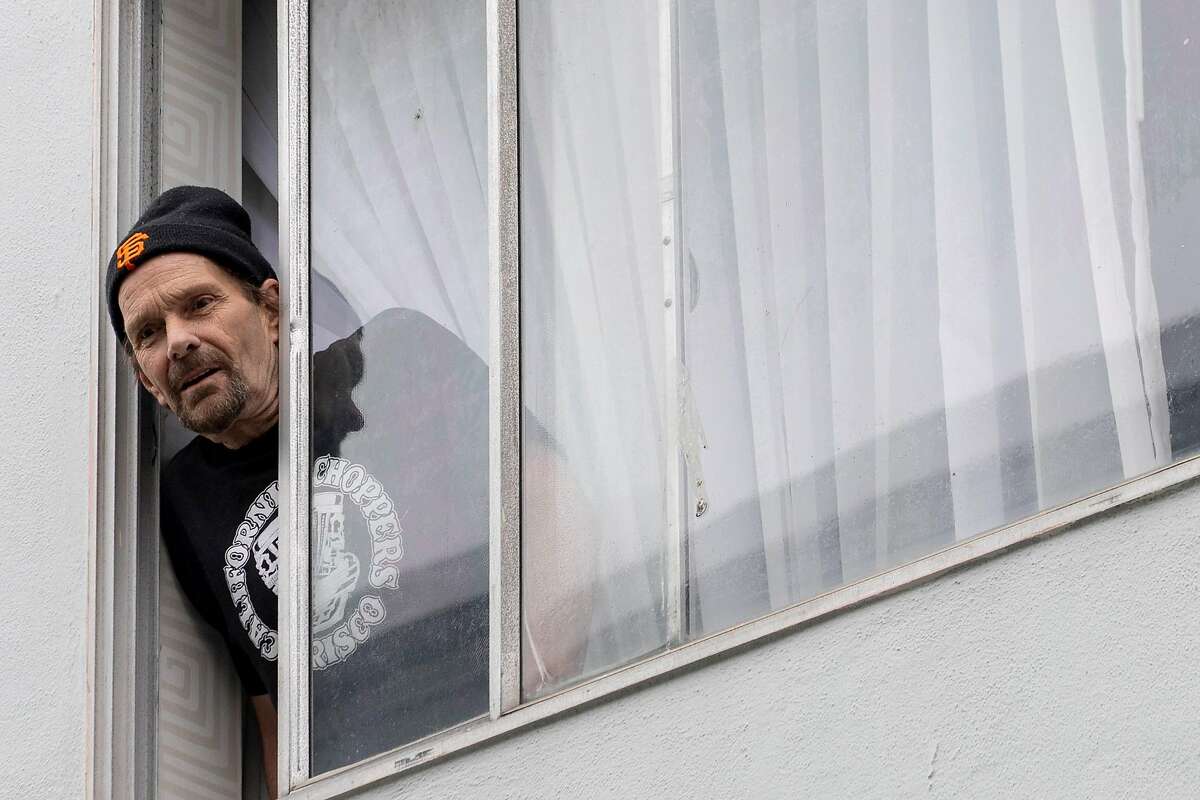 Mark Masonete, 64, poses for a portrait in the window of his hotel room in San Francisco, Calif. Thursday, April 16, 2020. Thousands of homeless people are being moved out of shelters and streets and into leased hotel rooms during the Coronavirus outbreak.