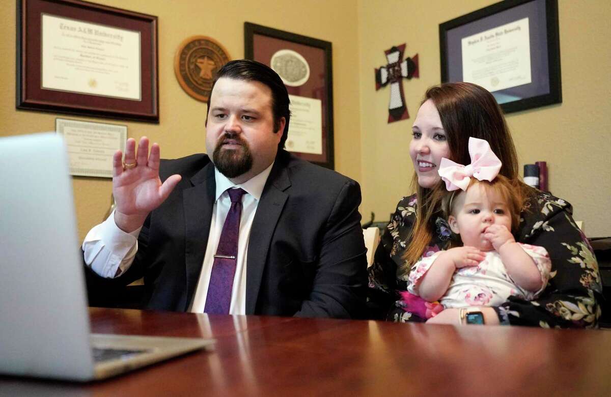 Case Towslee, left, with his wife, Traci Towslee, and their 9-month-old daughter, Caroline, is sworn in as a lawyer via a Zoom meeting at their home Monday, April 27, 2020, in Spring. The recent South Texas College of Law Houston graduate was sworn in online by state Supreme Court Justice Brett Busby.