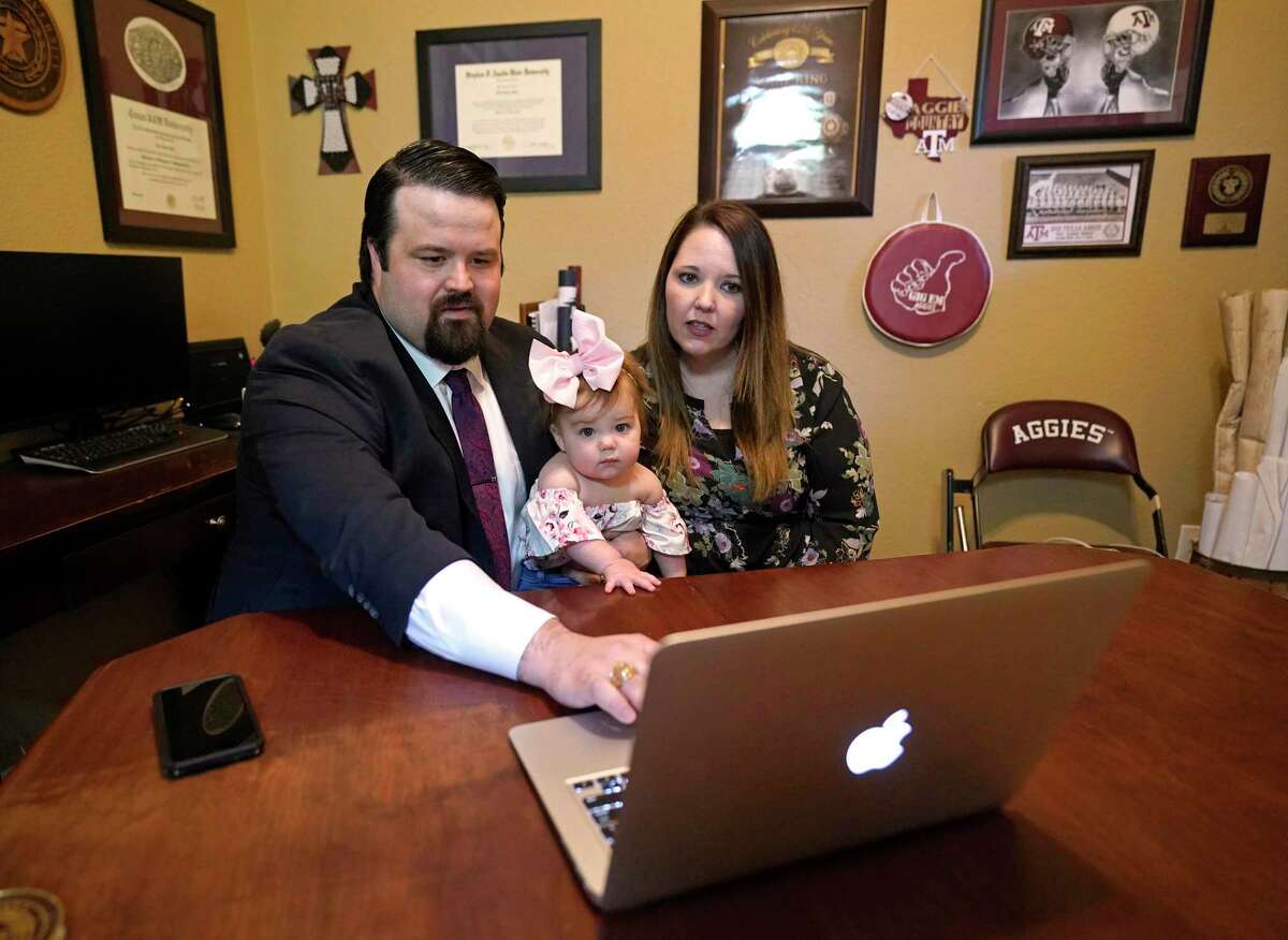 Case Towslee, left, with his wife, Traci Towslee, and their 9-month-old daughter, Caroline, prepares to be sworn in as a lawyer via a Zoom meeting at their home Monday, April 27, 2020, in Spring. The recent South Texas College of Law Houston graduate was sworn in online by state Supreme Court Justice Brett Busby.
