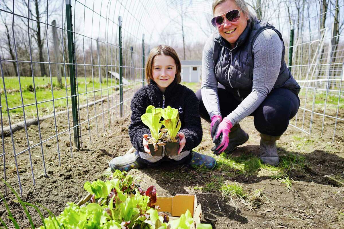Stella Marcy, 10, left, and her mom, Jes Marcy, pose in their family garden on Thursday, April 23, 2020, in Poestenkill, N.Y. Stella is hold lettuce seedlings. (Paul Buckowski/Times Union)