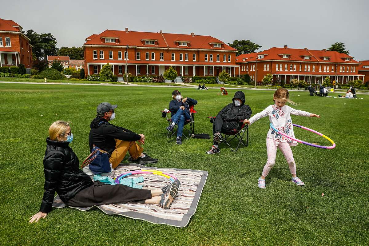 (L-r)Christina Dam, Jason Muscat, Becky Muscat and Bob Muscat watch as daughter and granddaughter Angie Muscat, 6, hula hoops while maintaining social distancing at the Main Parade Grounds in the Presidio in San Francisco, California on Sunday, April 26, 2020. Public health officials had feared spring-like weather over the weekend would cause a rush of people to set aside shelter in place mandates and descend upon public parks and beaches, putting themselves at risk to coronavirus exposure.