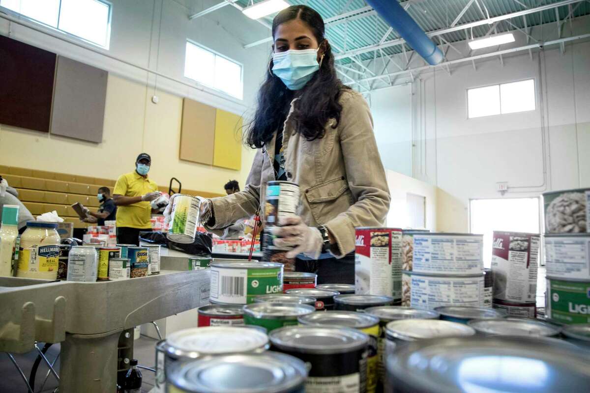 Ashley Khan sorts canned goods as she works to sanitize and sort dry goods on Thursday, April 16, 2020 at the Julia C. Hester House recreation center in Houston. Harris County Commissioner Rodney Ellis is teaming with the Houston Food Bank to provide food to residents impacted by coronavirus.