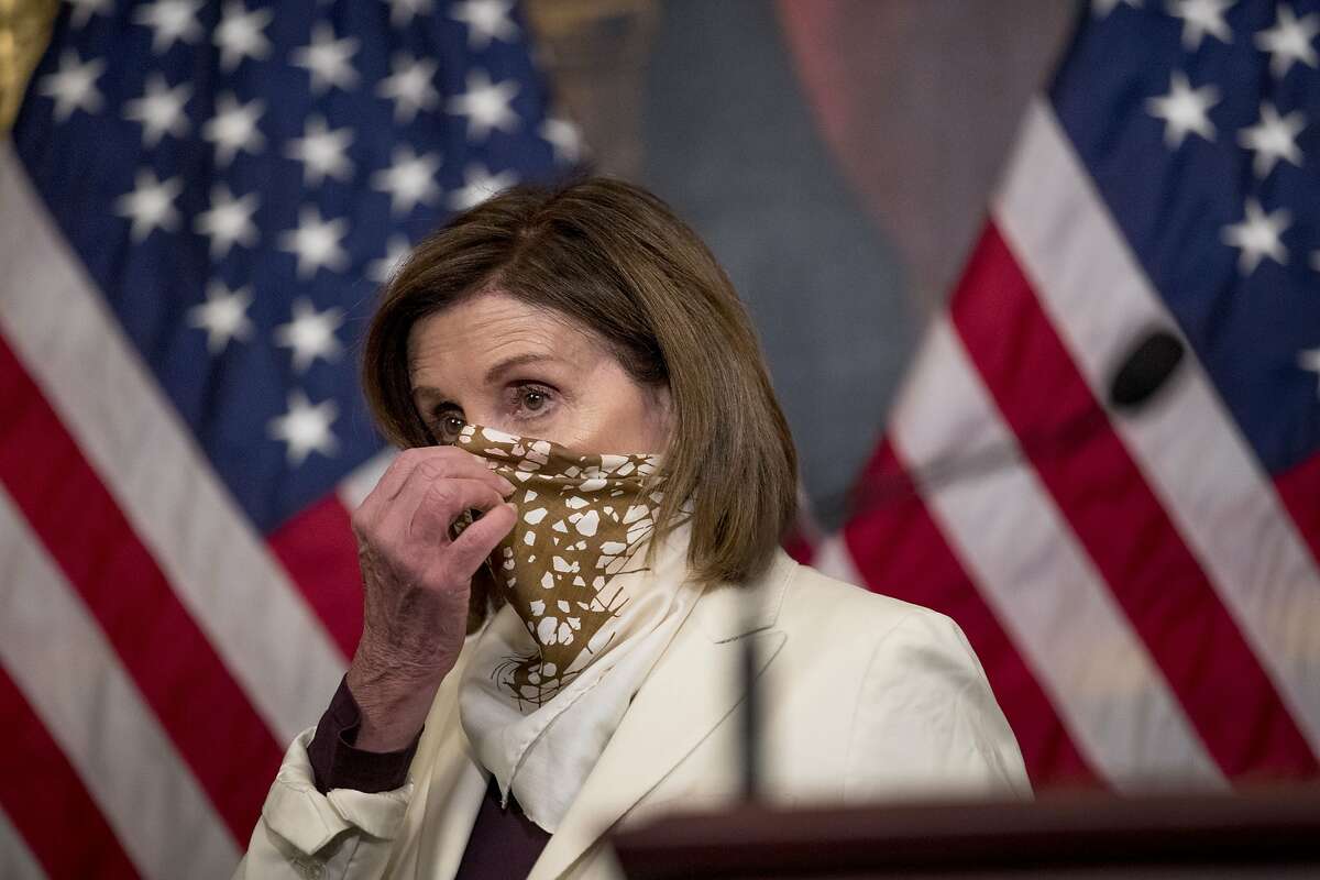 House Speaker Nancy Pelosi of Calif., puts on her scarf after signing the Paycheck Protection Program and Health Care Enhancement Act, after it passed the House on Capitol Hill, Thursday, April 23, 2020, in Washington. The almost $500 billion package will head to President Donald Trump for his signature. (AP Photo/Andrew Harnik)