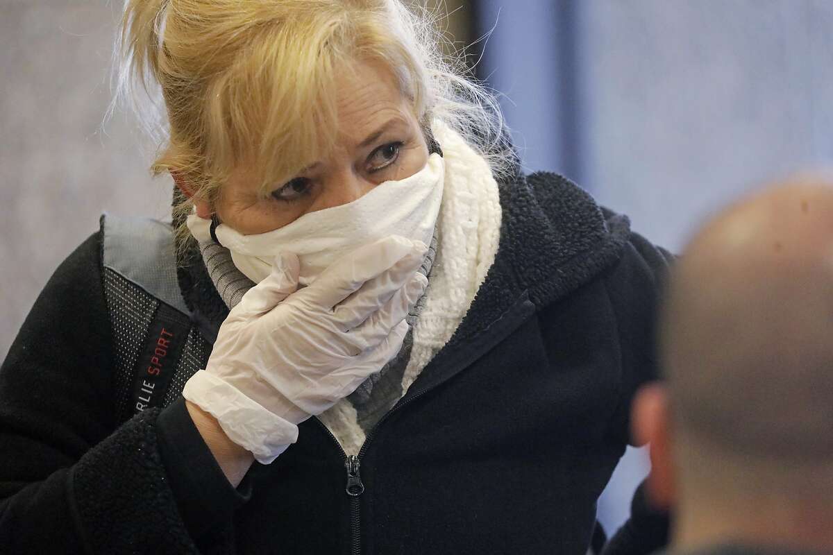 Passengers Gisela Sanchez covers her face at Salt Lake City International Airport Tuesday, April 7, 2020, in Salt Lake City. Airlines are suffering significantly as governments around the world urge people to stay at home to slow the spread of the coronavirus. The number of travelers screened last Thursday at U.S. airports was down 95% from the same day last year. Airlines such as Delta, American, United, Southwest and JetBlue have said they are applying for their share of $25 billion in federal grants designed to cover airline payrolls for the next six months. (AP Photo/Rick Bowmer)