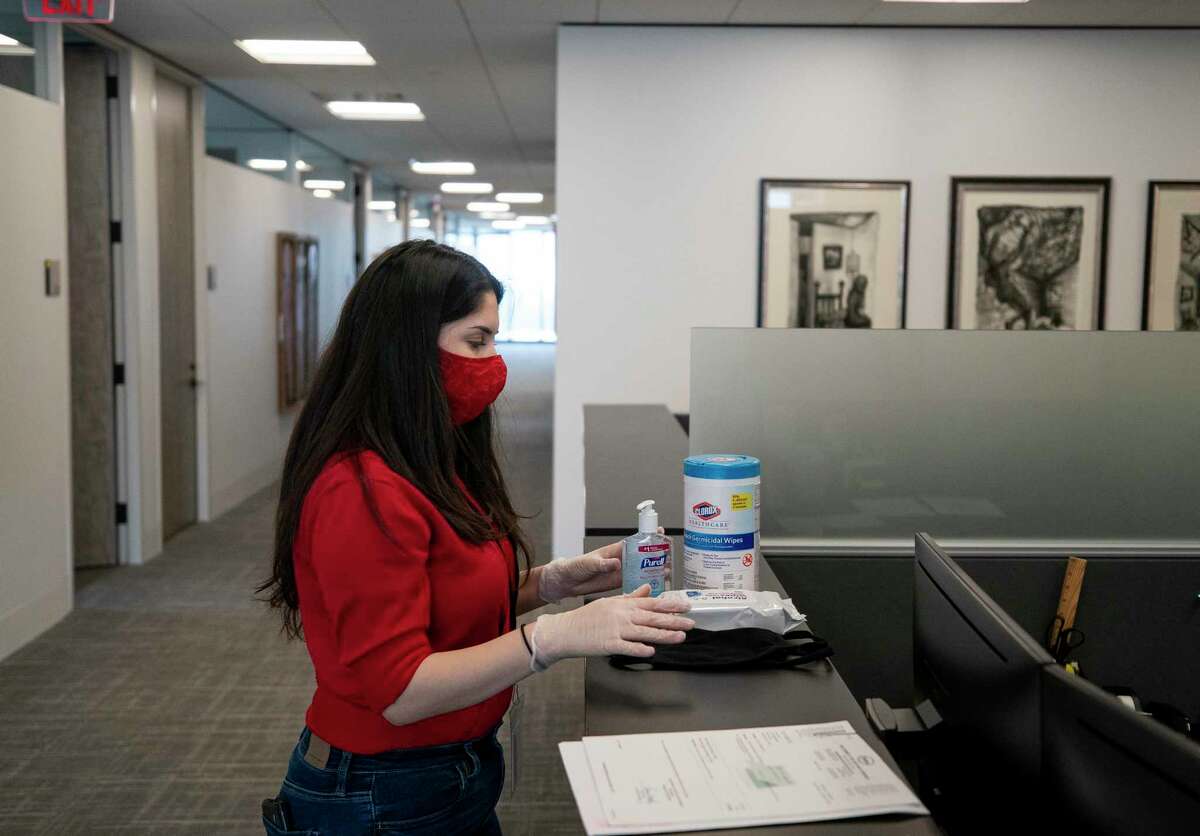 Alejandra Ramos, 23, a junior paralegal clerk at AZA Law, disinfecting products and face masks to place at work stations Monday, April 27, 2020, in Houston. Many companies are preparing for their employees to return to work.