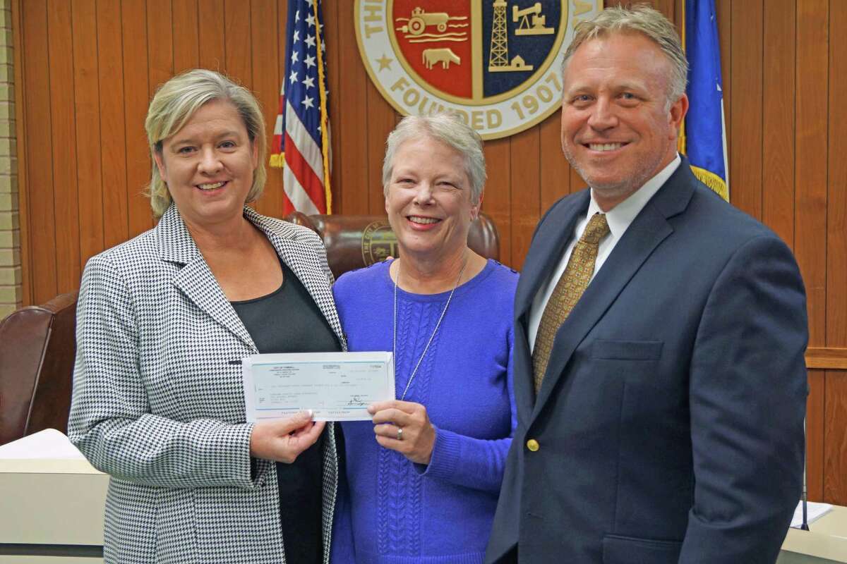 TOMAGWA executive director Judy Deyo receives a check for $10,836 from Tomball Mayor Gretchen Fagan and Assistant City Manager Rob Hauck during a recent meeting of the Tomball City Council.