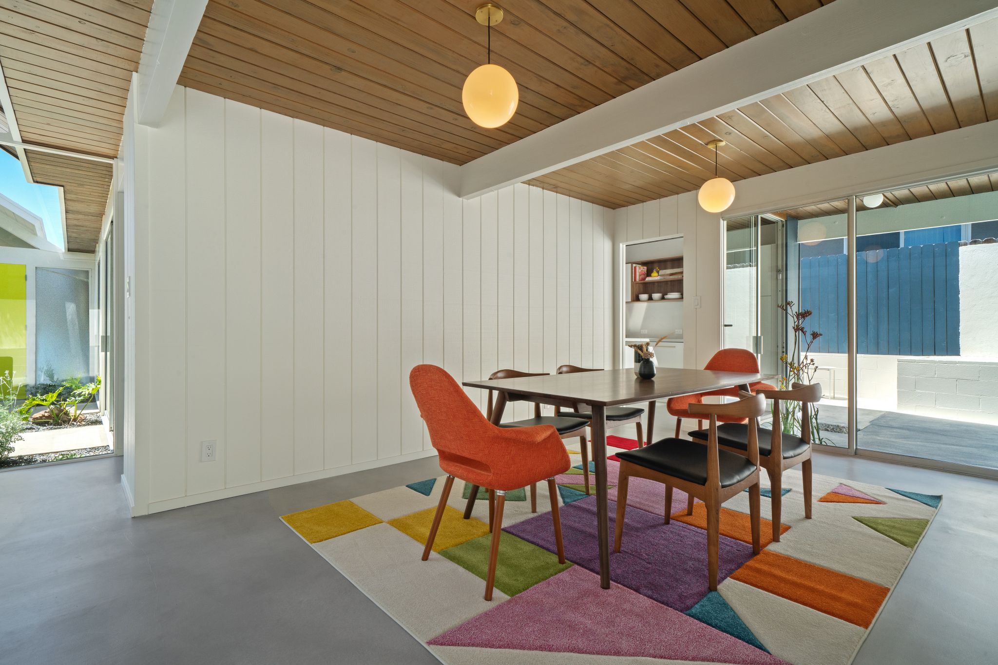 The formal dining room is retro magic, from the paneled walls and ceiling to the golden globular light fixtures.