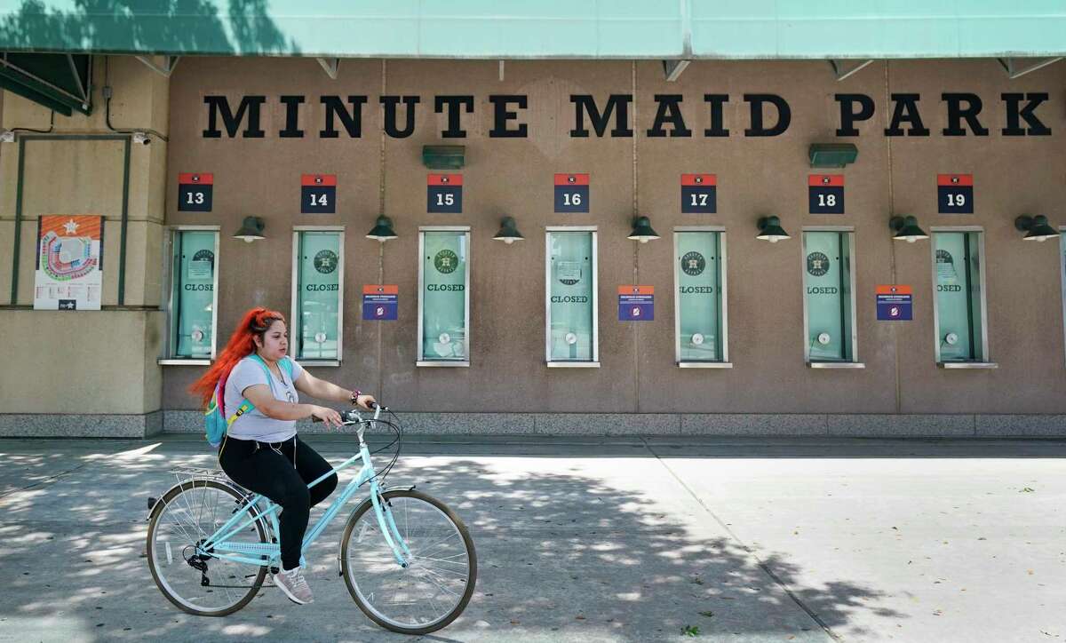 A bicyclist rides by the closed Houston Astros ticket windows at Minute Maid Park is shown Wednesday, April 29, 2020, in Houston. Major League Baseball delayed the start of the season amid the Covid-19 pandemic.