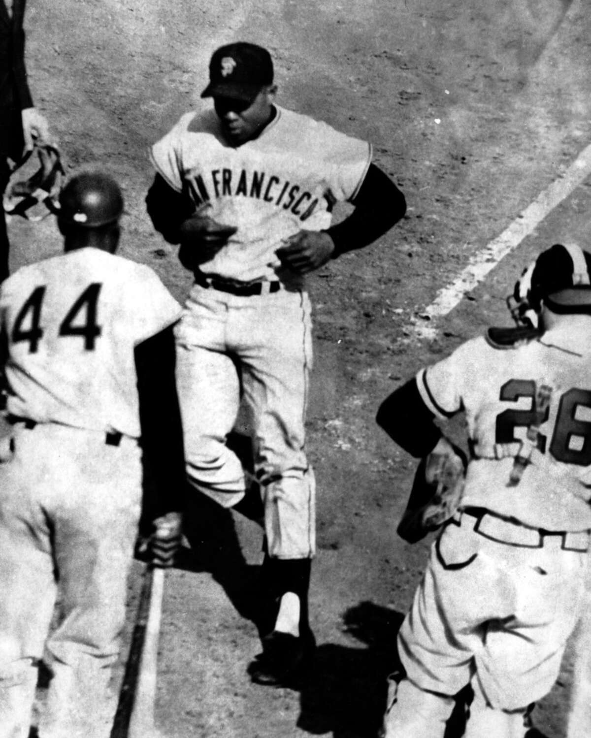Willie Mays, center, jogs toward home plate after his fourth homer in the eighth inning against the Braves on April 30, 1961 in Milwaukee. Willie McCovey, left, and Braves catcher Hawk Taylor, right, watch the run score.