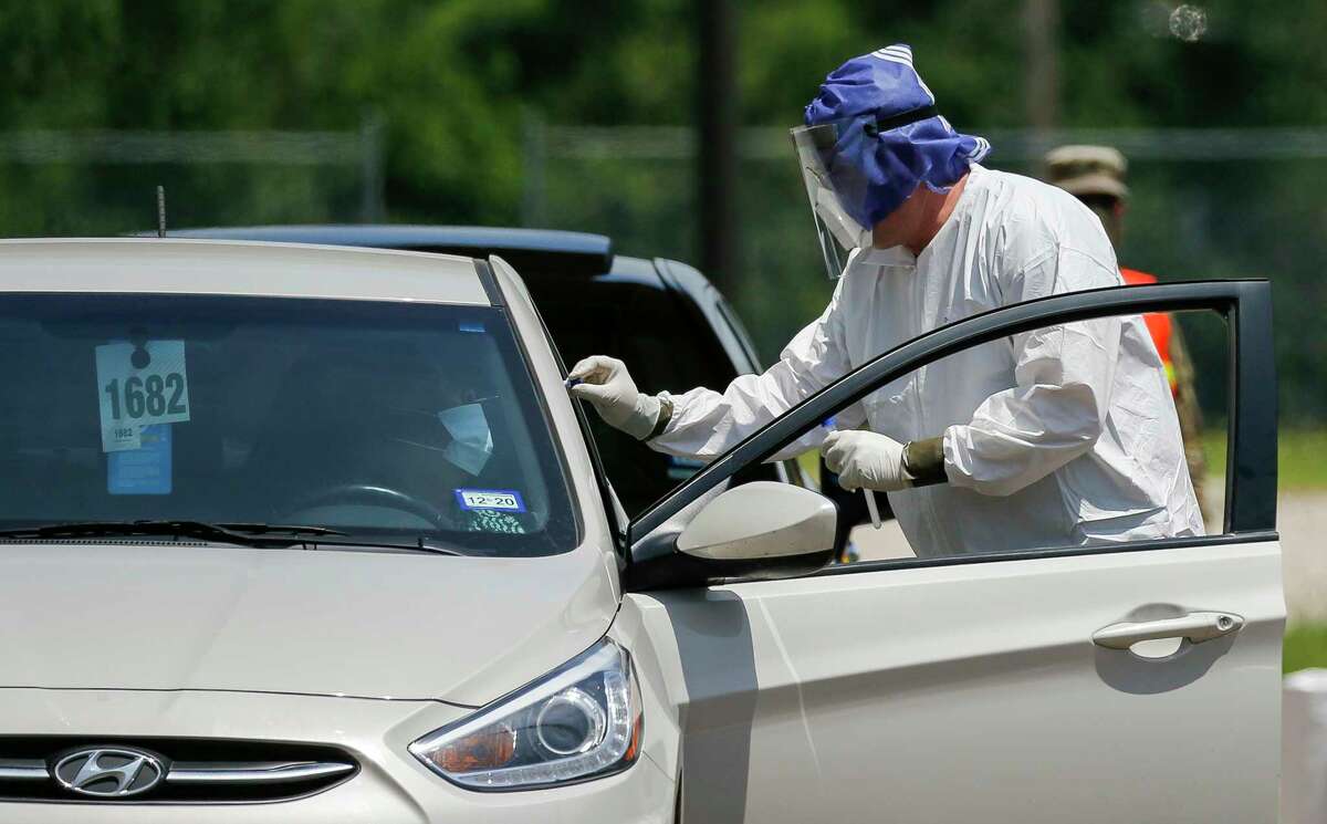 A health professional conducts a COVID-19 test on a motorist at Worthing High School on Wednesday, April 29, 2020, in Houston.