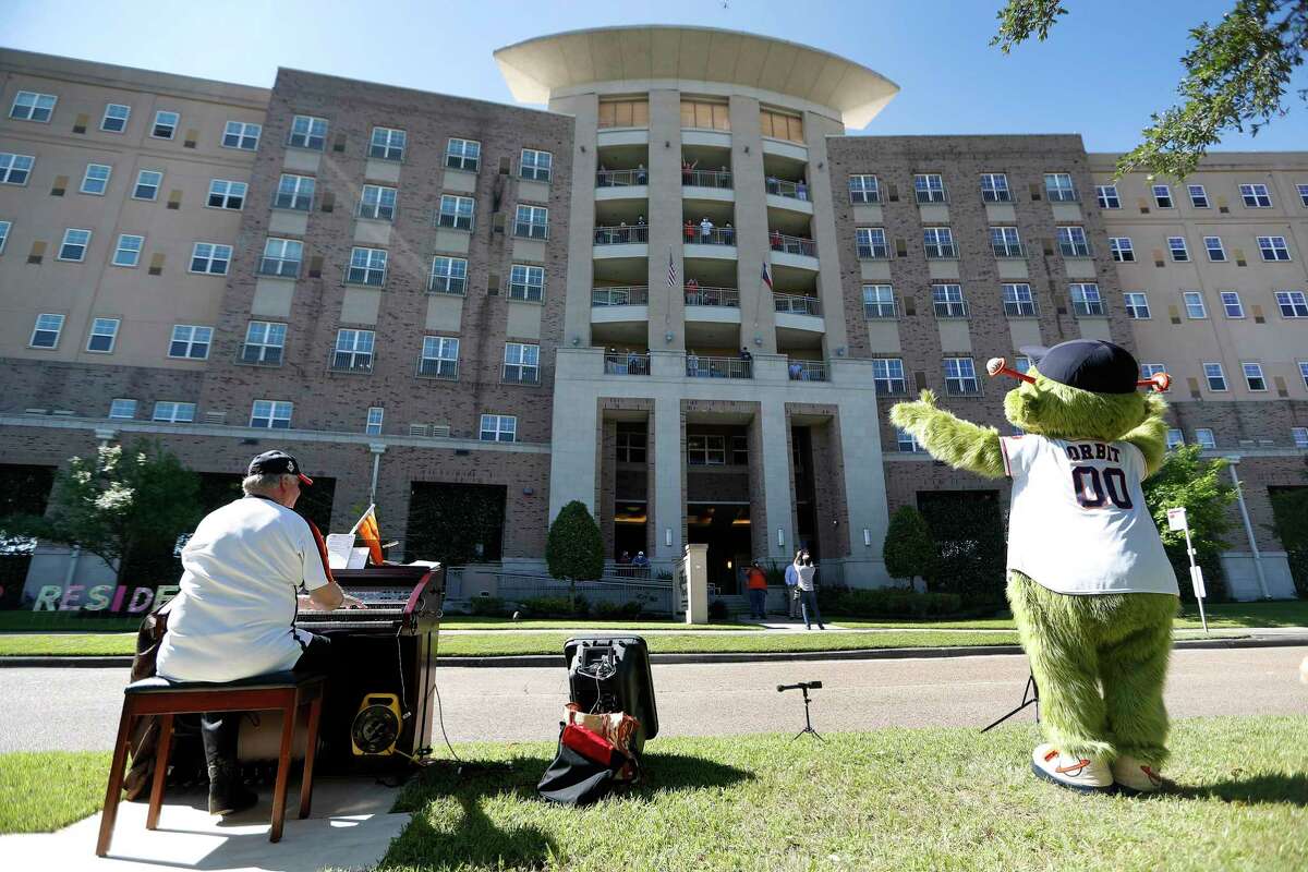 Former Astros organist, Jim Connors, sings and plays the organ while Orbit danced nearby, as Conners presented his 7th Inning Stretch Show from the esplanade on North Braeswood Boulevard, to six floors of cooped-up, seniors at the Village of Meyerland, in Houston, Thursday, April 30, 2020.