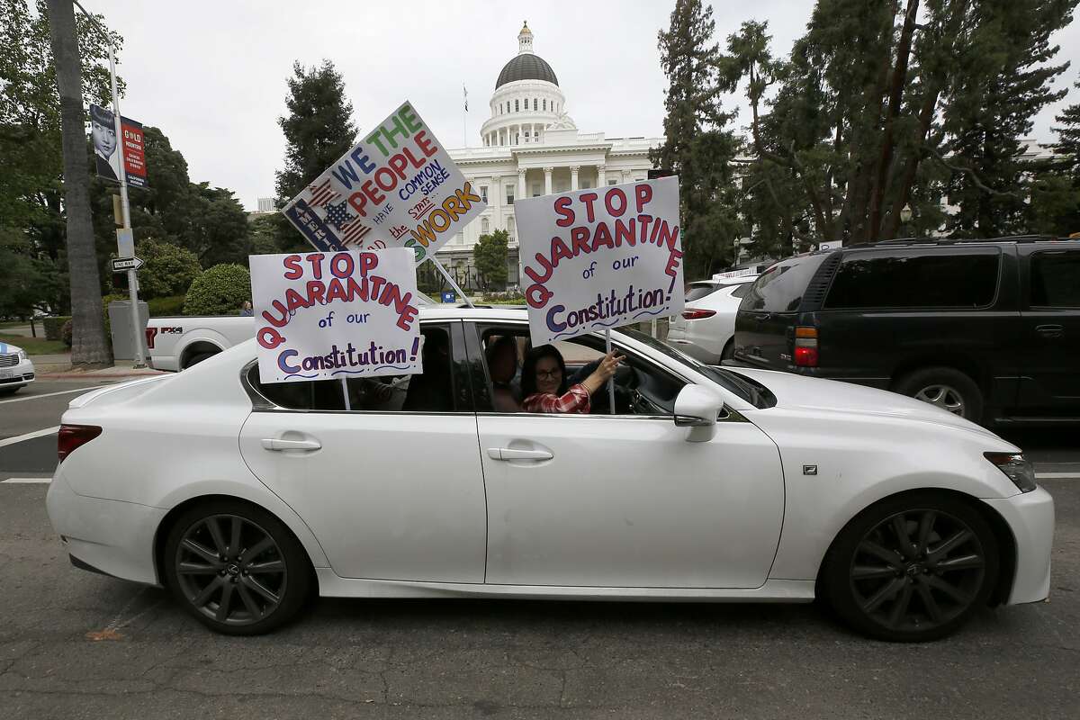A car carrying protesters calling for the end Gov Gavin Newsom's stay-at-home orders passes the state Capitol in Sacramento, Calif., Monday, April 20, 2020. Several hundred people gathered at the Capitol calling for Newsom to ease the restrictions and allow people return to work.(AP Photo/Rich Pedroncelli,)