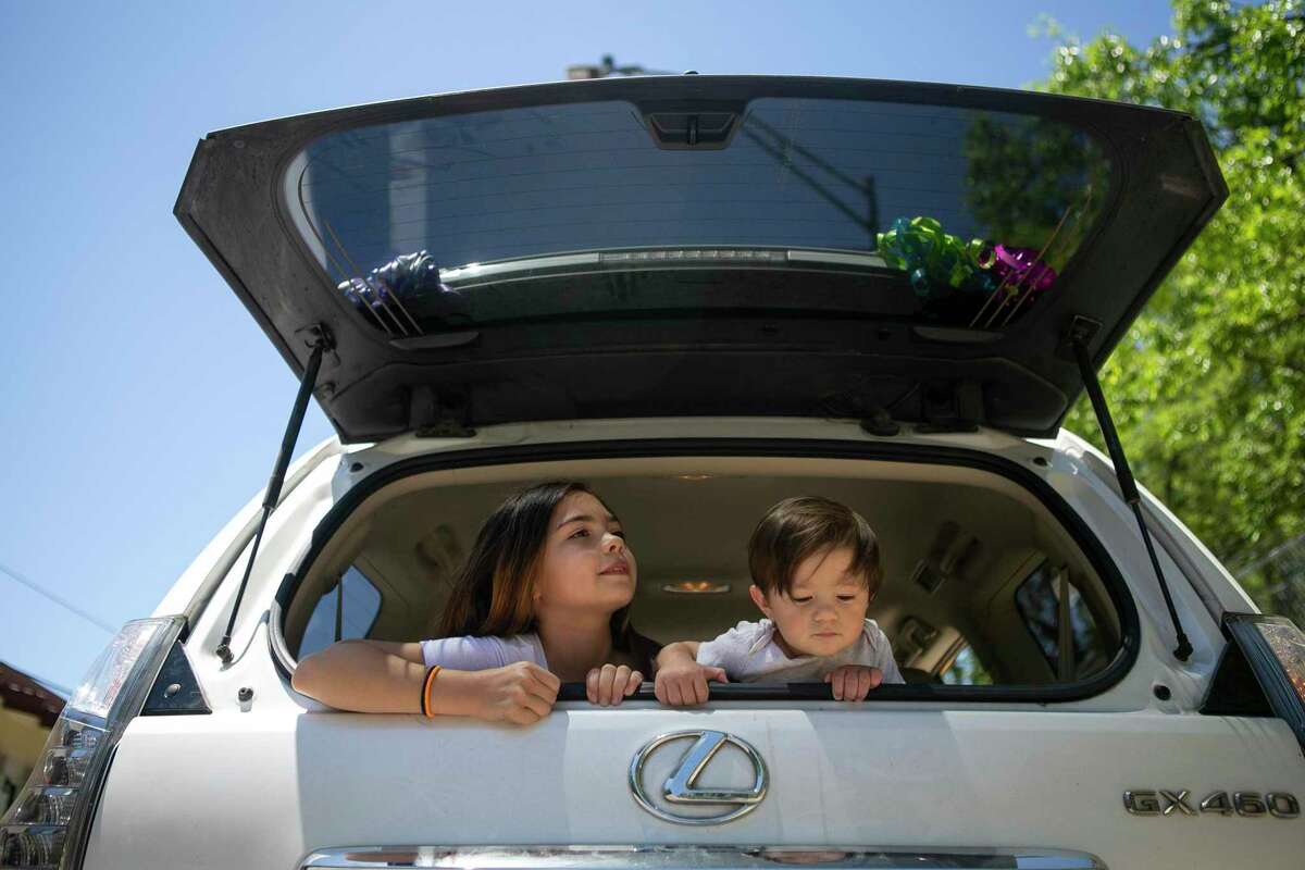 Lola Petrishian, 9, and her brother Michael Mihalski, III, 1, lean out the hatch of their mother's car before touring the new drive thru version of the San Antonio Zoo in San Antonio, Texas on April 30, 2020. The zoo will begin hosting more than 600 cars a day, that will drive down the pathway usually filled with visitors, for guests to look at animals while still practicing social distancing.