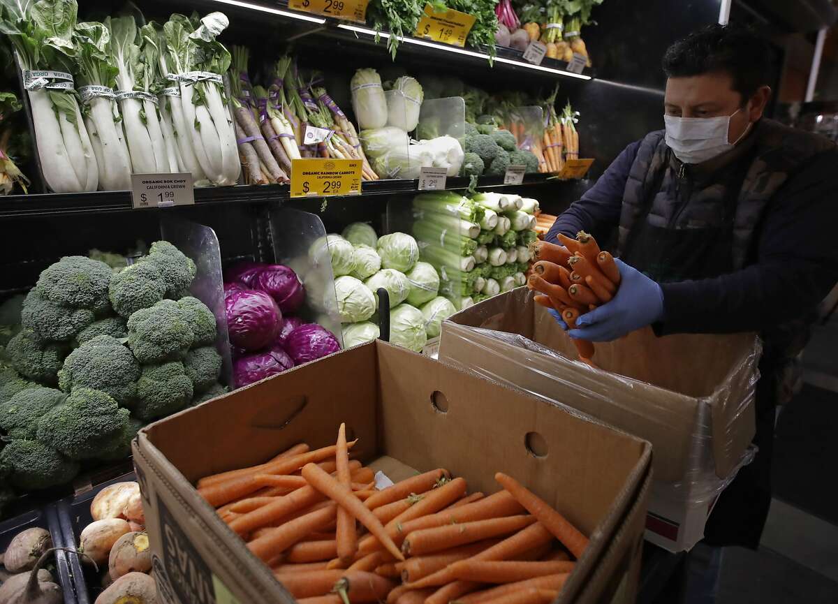 FILE - CalFresh recipients will no longer receive emergency allocations starting in April 2023. In this March 27, 2020, file photo, a worker, wearing a protective mask against the coronavirus, stocks produce before the opening of Gus's Community Market in San Francisco.