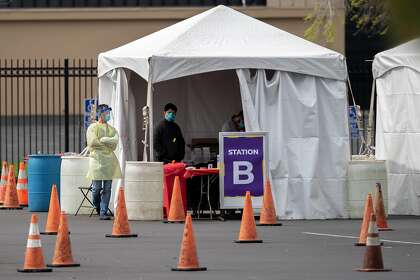 Health officials at a Verily coronavirus drive-through test clinic wait for patients to instruct and verify before directing them inside the San Mateo County Event Center on March 17, in San Mateo. County officials on Thursday started releasing information on cases by zip code.