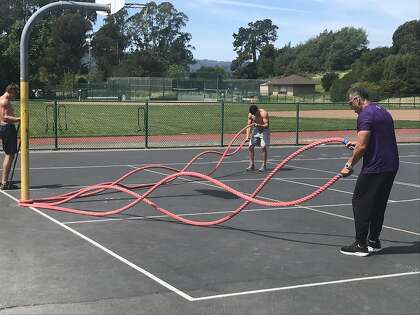 Rich Juarez (right) and college football player Hunter Juarez do a drill with a battle rope in Tiburon.