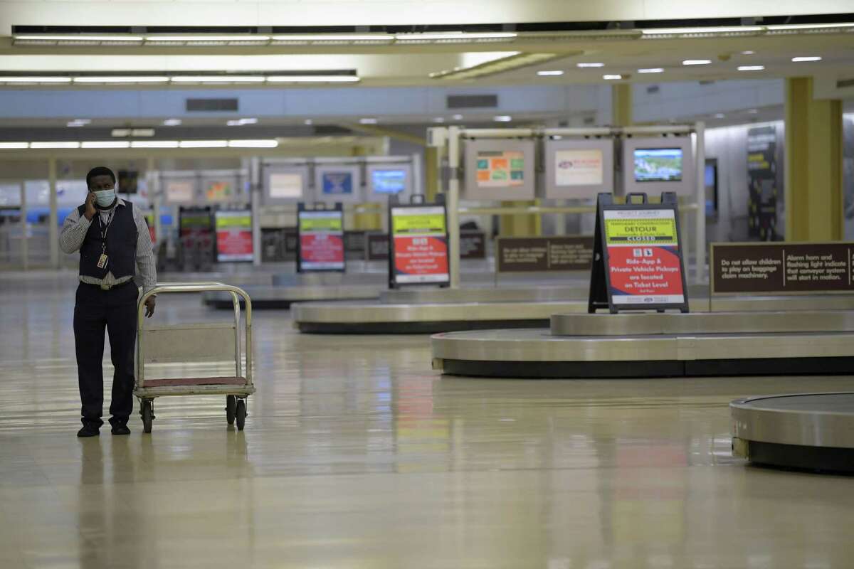 An American Airlines worker walks in a deserted baggage claim area at Reagan National Airport in Arlington on Friday. (