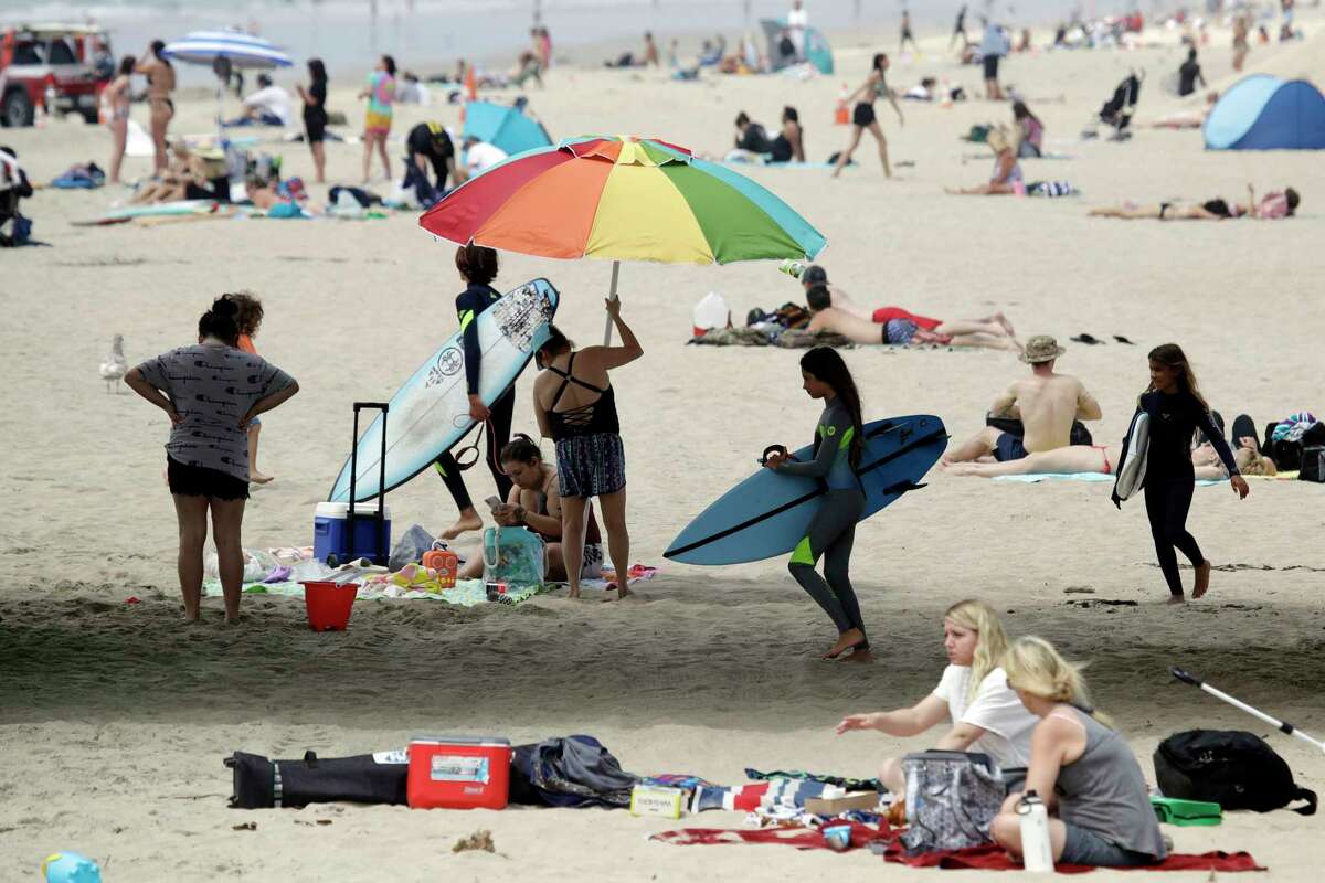 Beach goers converge under a pier Thursday, April 30, 2020, in Huntington Beach, Calif. California Gov. Gavin Newsom has ordered beaches in Orange County to close until further notice amid the COVID-19 pandemic. Newsom made the announcement Thursday, days after tens of thousands of people in Orange County packed beaches during a sunny weekend.