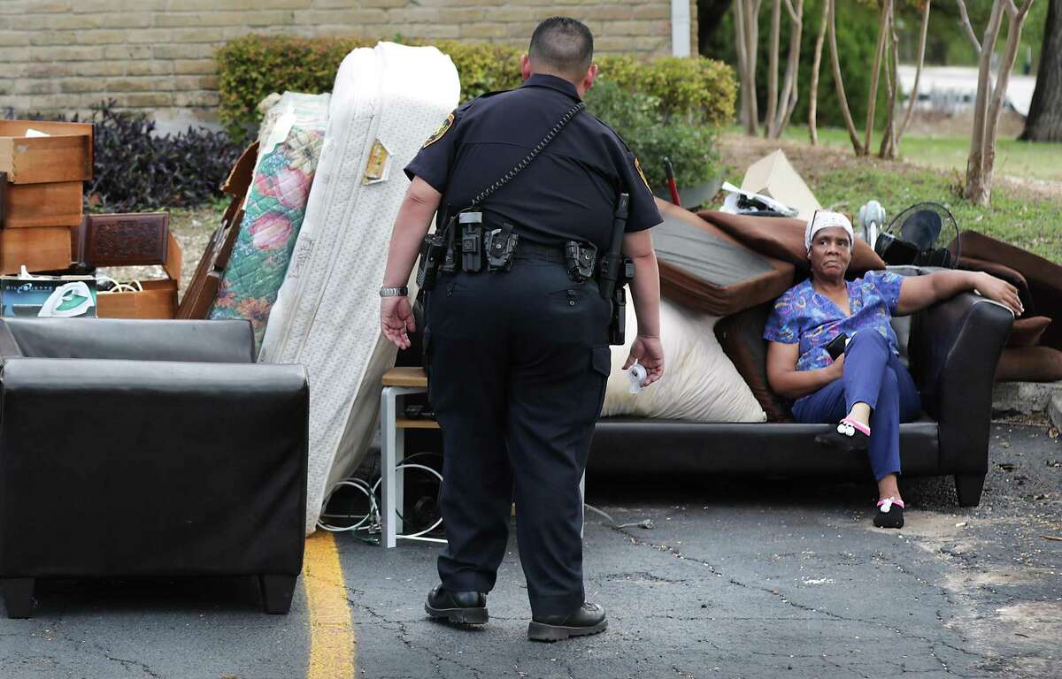 Bexar County Deputy Constable Edward Prado of Precinct 4, center, checks on Patricia A. White as she sits with her possessions after Prado served a writ of possession to White at Brooks Townhomes on Wednesday, Nov. 6, 2019.