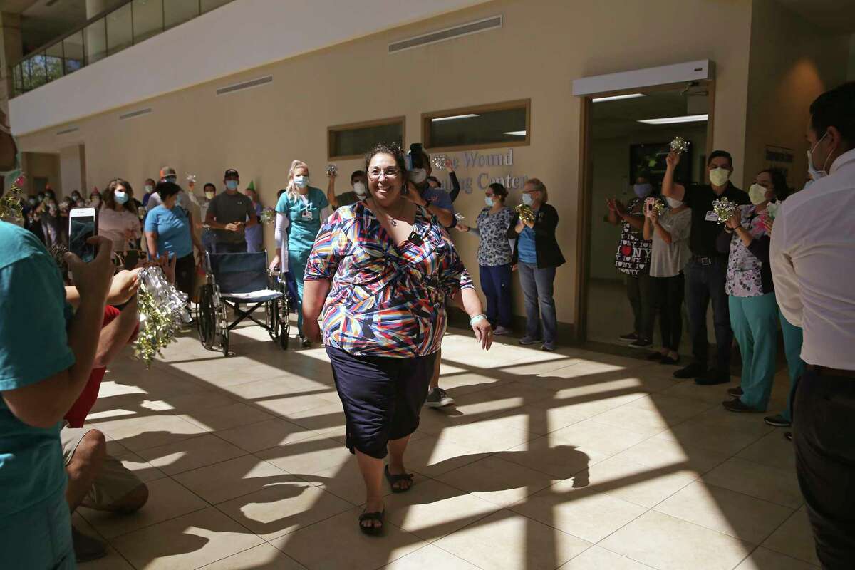 Northeast Baptist Hospital cheer Pamela Oakley as she walks out after surviving a near-fatal case of COVID-19. She spent three weeks on a ventilator and wasn't expected to survive.