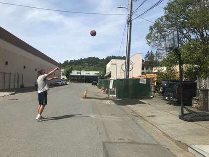 Rob Fordyce shoots a basketball in front of his house in San Rafael. He also hits tennis balls against a building.