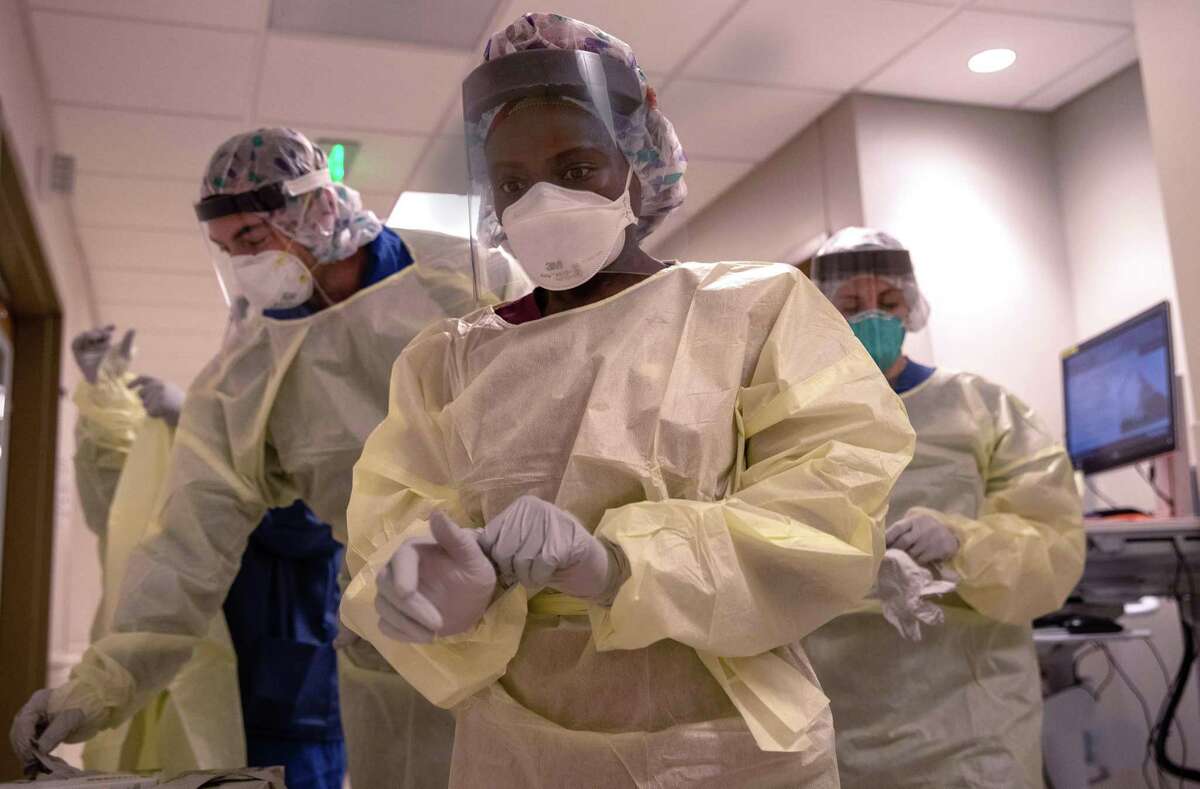 A member of a "prone team," dons personal protective equipment, before entering the room of a patient with COVID-19 in a Stamford Hospital intensive care unit (ICU), on April 24, 2020 in Stamford, Connecticut. The civilian/military team, made up of physical and occupational therapists turns over COVID-19 patients to help their labored breathing and increase lung capacity.