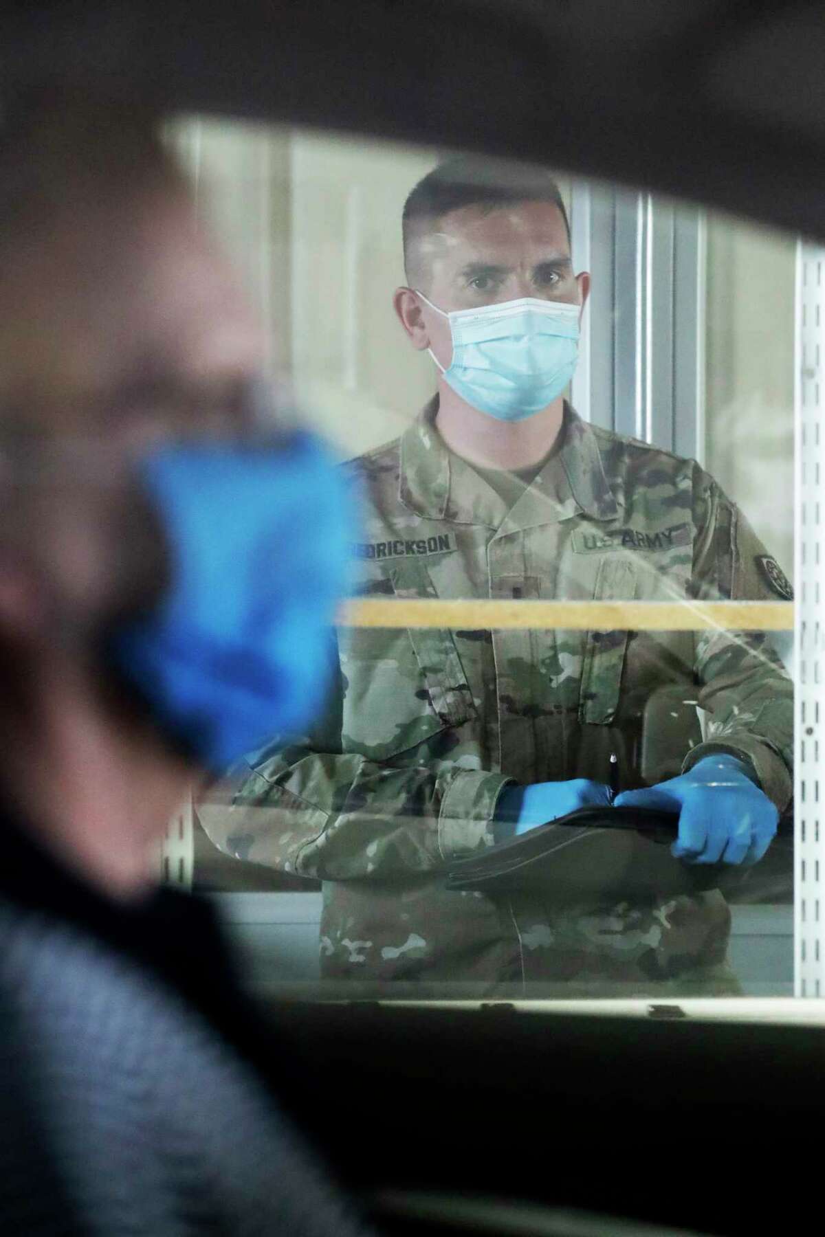 A member of the Illinois National Guard looks at a man at the testing facility site in Waukegan, Ill., Saturday, May 2, 2020. A drive-thru COVID-19 testing facility, the state's first community-based site in Lake County, will open for the public in Waukegan on Sunday, May 3.