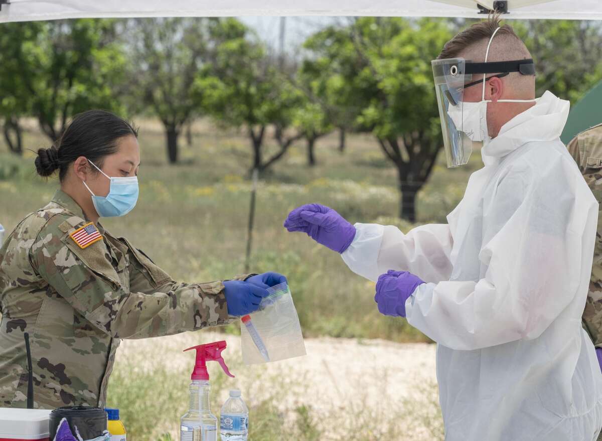 Sgt. Jon Murphy, medic with the 2nd 142nd INF out of Lubbock, TX, hands the nasal swab to Pvt. First Class Kelly Nguyen as they and other members of the Texas Military Forces, including the Texas Army National Guard, Texas Air National Guard, and Texas State Guard, conduct coronavirus testing 05/03/2020 at the Greenwood Volunteer Fire Department. The testing is free and open to anyone, but appointments had to be made in advance. Tim Fischer/Reporter-Telegram
