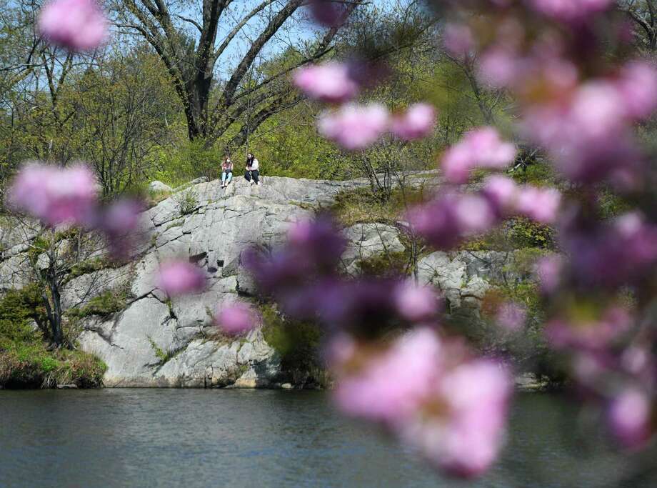 Two people sit on a rock overlooking the water at Bruce Park on a sunny day in Greenwich, Conn. Sunday, May 3, 2020. With a high temperature in the upper-70s, the town saw lots of exhausted quarantiners active on the streets and in the parks. Photo: Tyler Sizemore / Hearst Connecticut Media / Greenwich Time