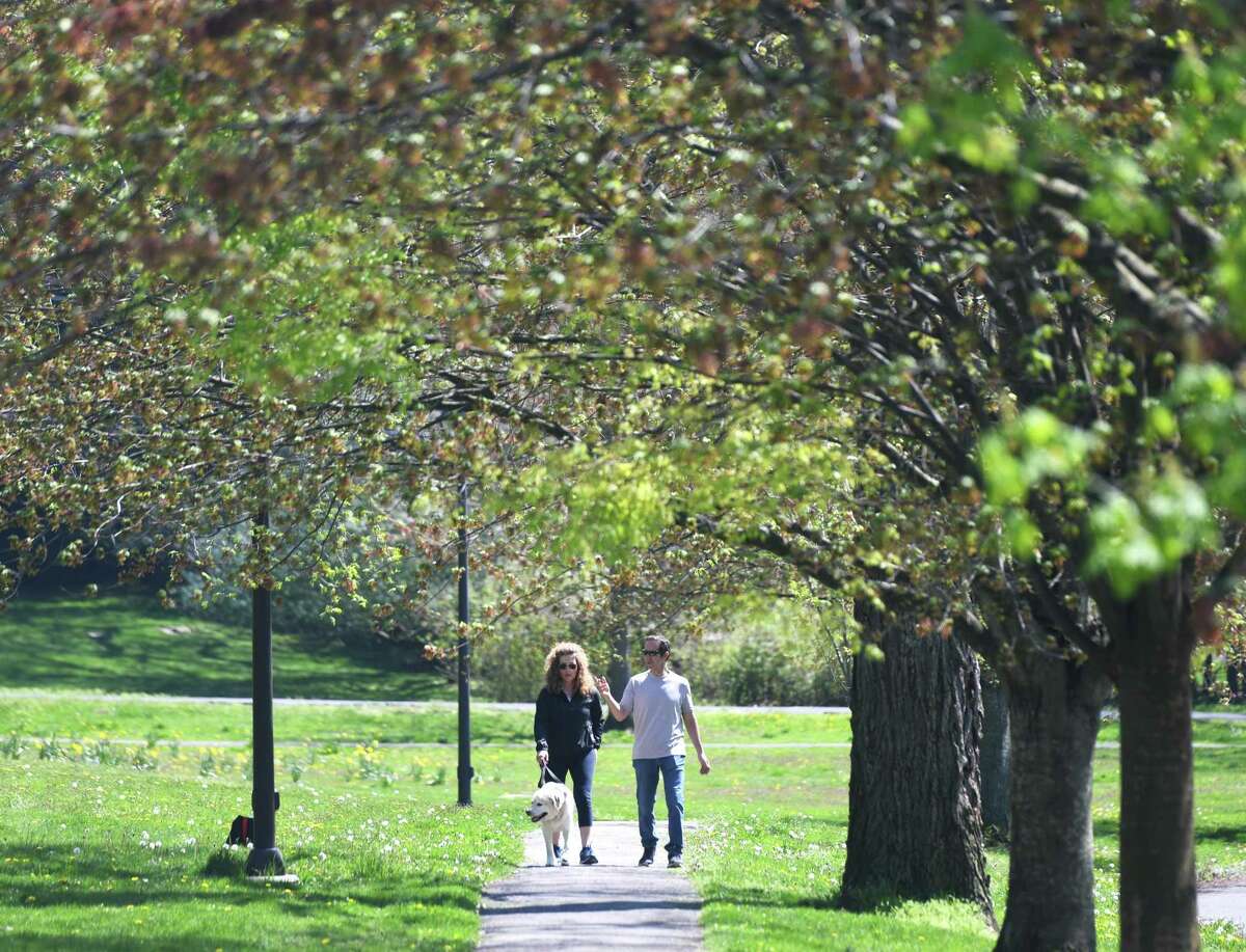 Cos Cob's Arlene and Tony Chioditti walk their dog, Riley, through Bruce Park on a sunny day in Greenwich, Conn. Sunday, May 3, 2020. With a high temperature in the upper-70s, the town saw lots of exhausted quarantiners active on the streets and in the parks.