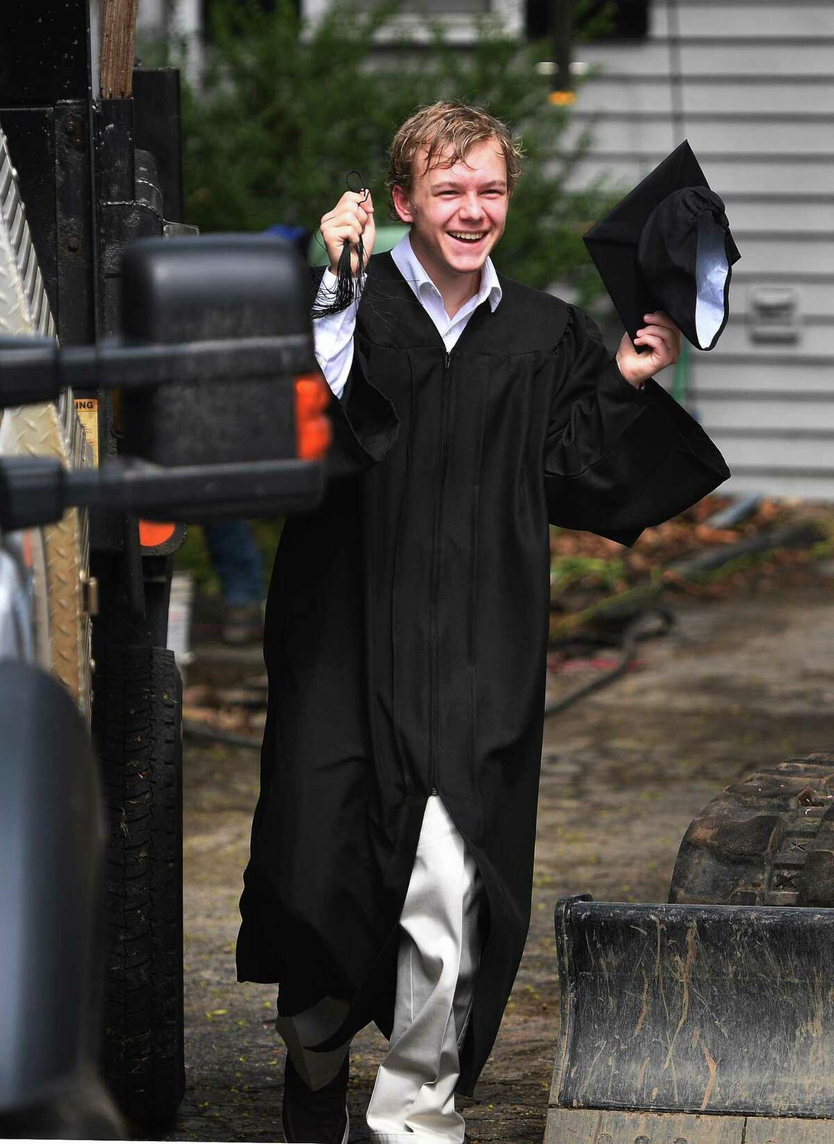 P-Tech program graduate Landon Heatley greets program staffers as he comes out to take cap and gown photos outside his home in Norwalk, Conn. on Sunday, May 3, 2020. Staffers in a car caravan visited each of the program graduates for photos on Sunday.