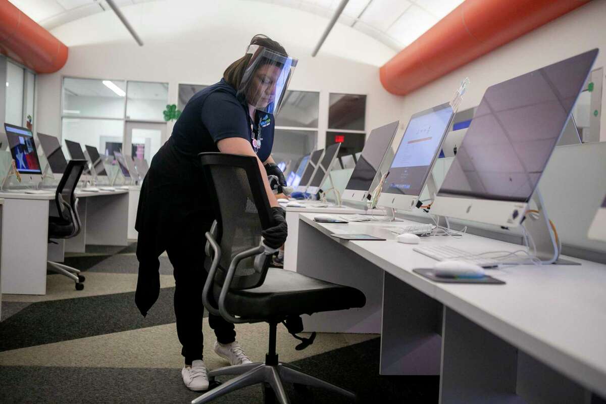 Marisa Torres cleans computer stations at BiblioTech South in San Antonio on May 4, 2020. BiblioTech, Bexar County’s all-digital library system, reopened branches at 25 percent capacity with limited services. San Antonio will begin reopening its libraries June 15.