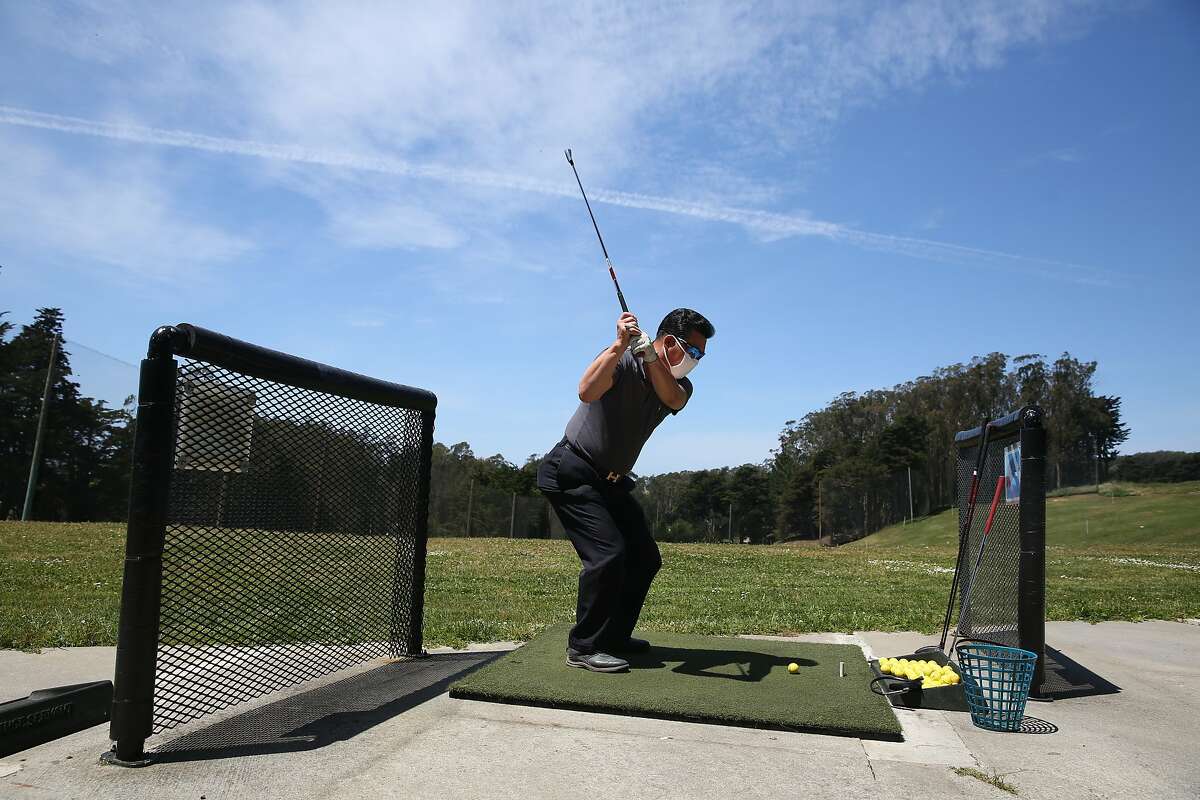 Song Hong of San Francisco hits golf balls on the driving range where golfers kept one empty space between them at the Presidio Golf Course on Monday, May 4, 2020 in San Francisco, Calif.