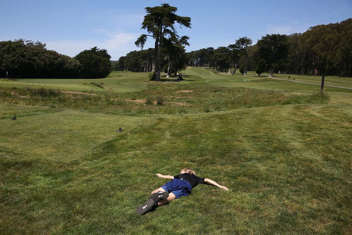 Luca, 11, of San Francisco lies in the grass at the Presidio Golf Course while enjoying some time outdoors with his mother and brother on Monday, May 4, 2020 in San Francisco, Calif.