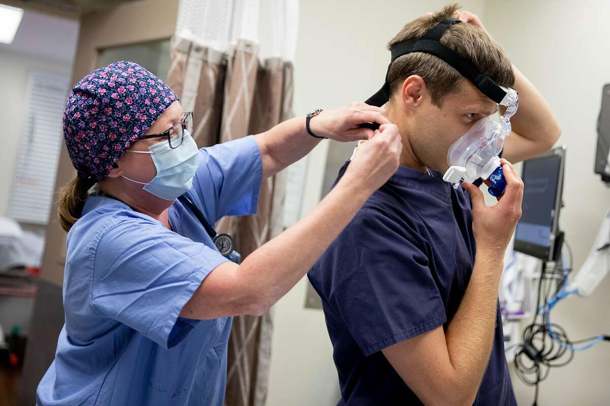 A respiratory therapist (no name given) assists emergency medicine physician Dr. Cotton Widdicombe as he demonstrates the use of a CPAP machine with a modified viral filter to assist COVID-19 patients with easy breathing while inside an exam room in the emergency department at Seton Medical Center in Daly City, Calif. Friday, May 1, 2020. As ER and ICU doctors gain a better understanding of previously unknown COVID-19 complications, such as blood clots, they are changing the way they care for patients. Doctors are now giving many patients blood thinners in light of emerging evidence that many are developing small and large blood clots that cause strokes. They're also finding that CPAP machines often work better to help patients breathe than ventilators, which were once thought to be a standard course of treatment for patients struggling to breathe.