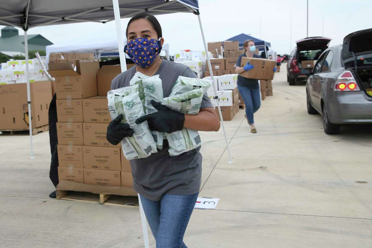 San Antonio District 4 Council Member Adriana Rocha hands out bags of frozen peas during a San Antonio Food Bank mega food distribution Tuesday at Traders Village.